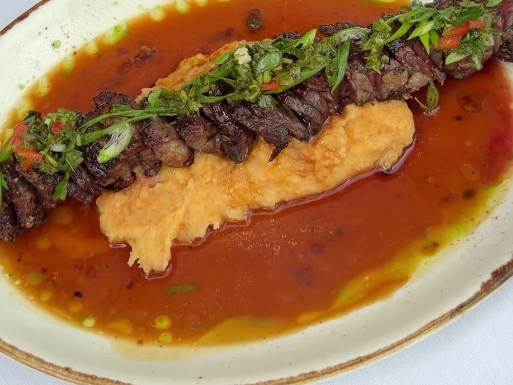Grilled meat served over a bed of hummus
